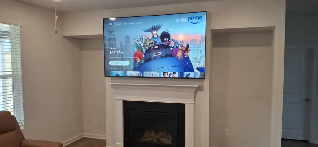 Television mounted flush over a white fireplace mantel with no visible cabling