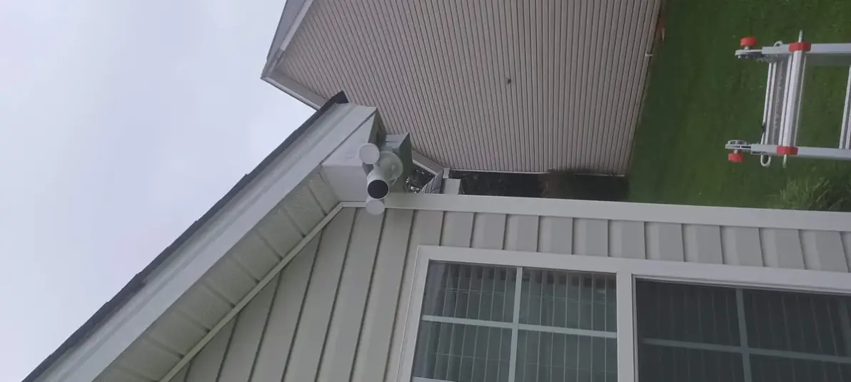 Close-up of an outdoor security camera mounted under a house eave