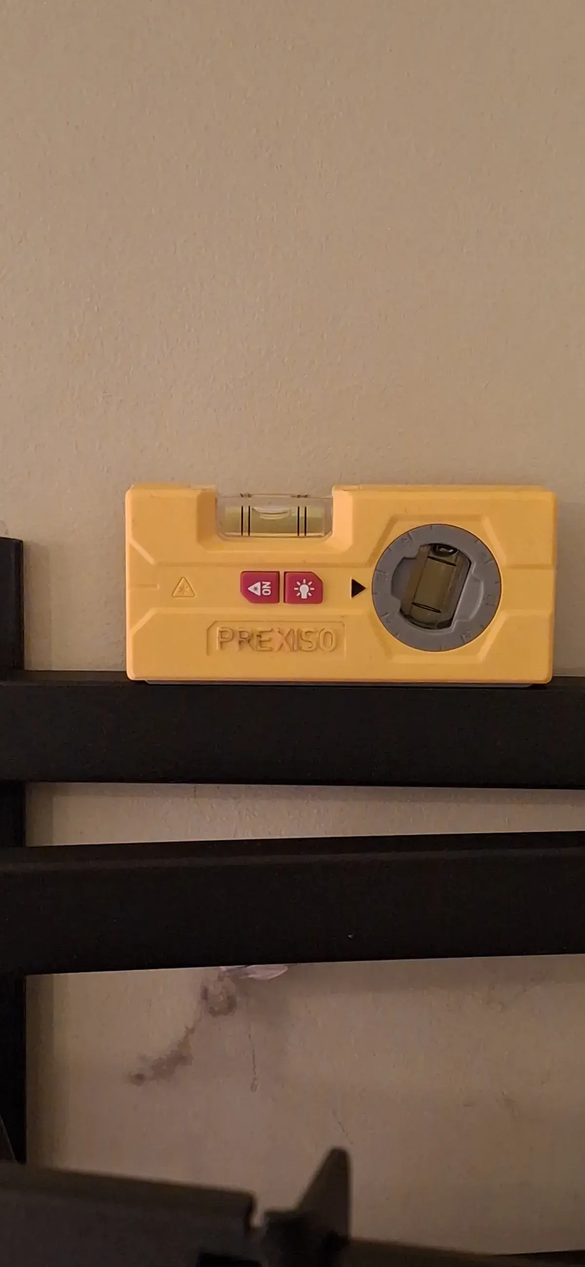 Torpedo level resting on a television mounting bracket rail during an install