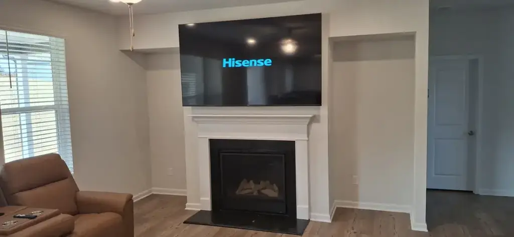 Television mounted flush above a white fireplace mantel in a Middle Georgia living room