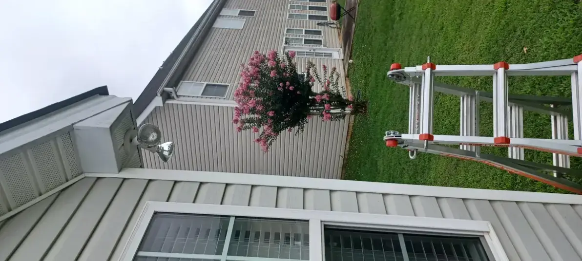 Exterior house eave with a floodlight fixture and a ladder on the lawn